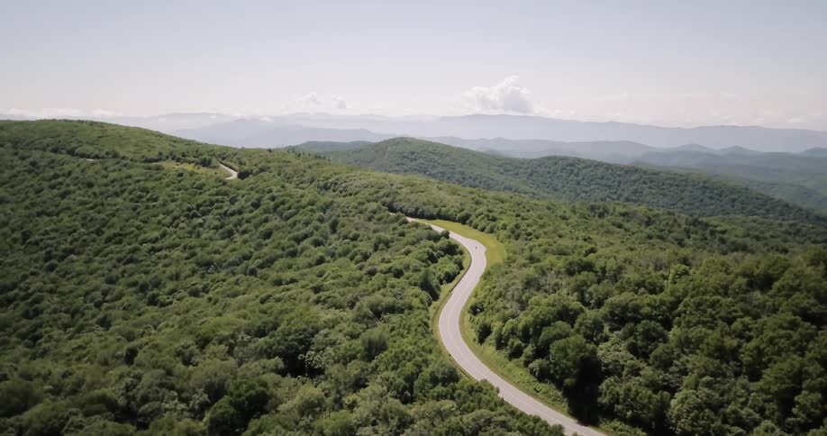 A motorcycle rides up a winding mountain road