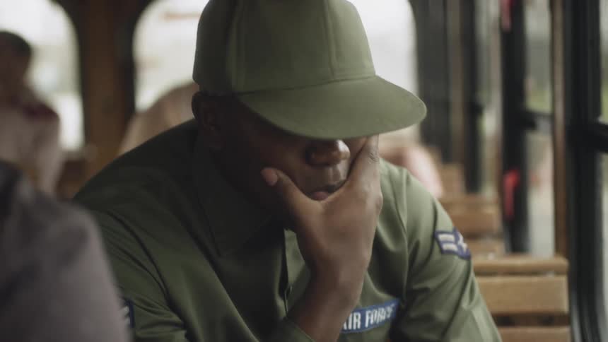 An airman sitting on a trolley rubs his face