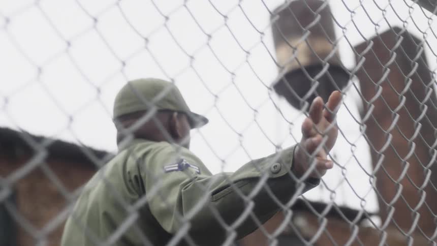 A service member walks next to a chain link fence