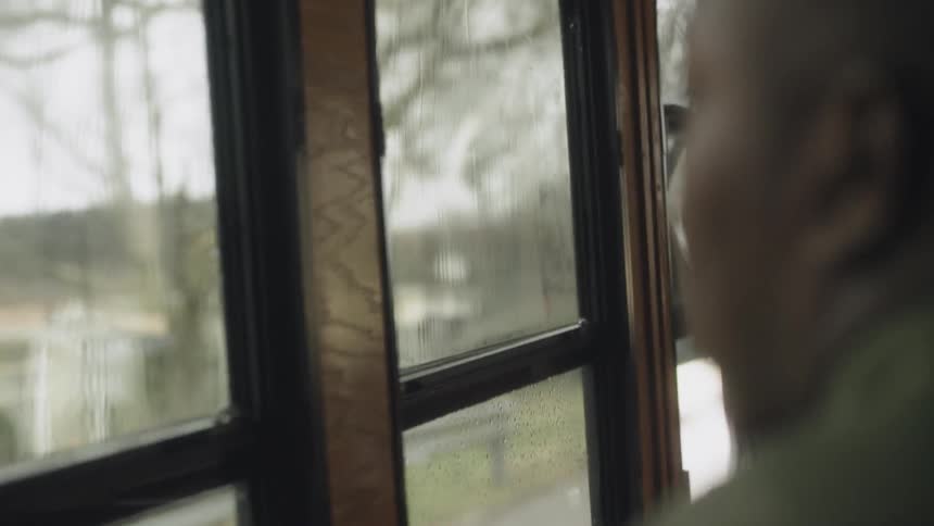 A man looks out the bus window at the homes in the neighborhood
