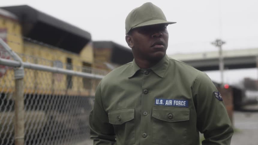 A service member walks next to a chain link fence
