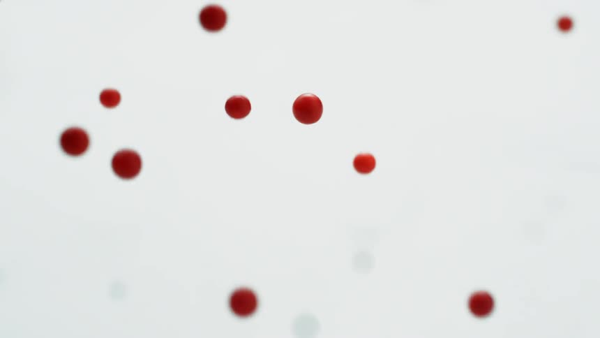 Red berries fall onto a white surface and bounce