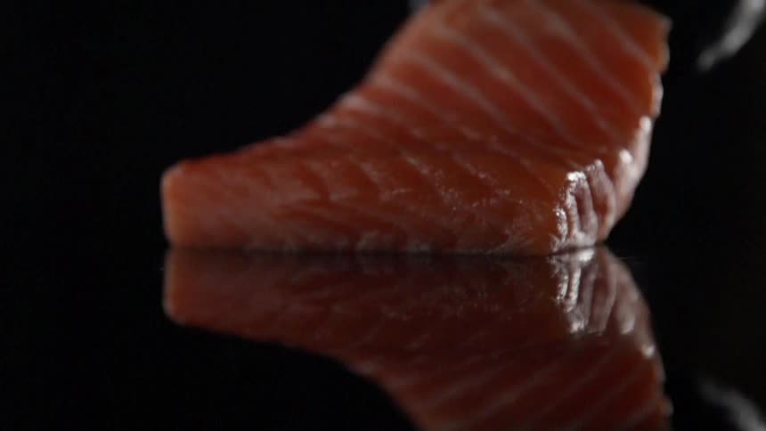A piece of salmon is dropped onto the counter