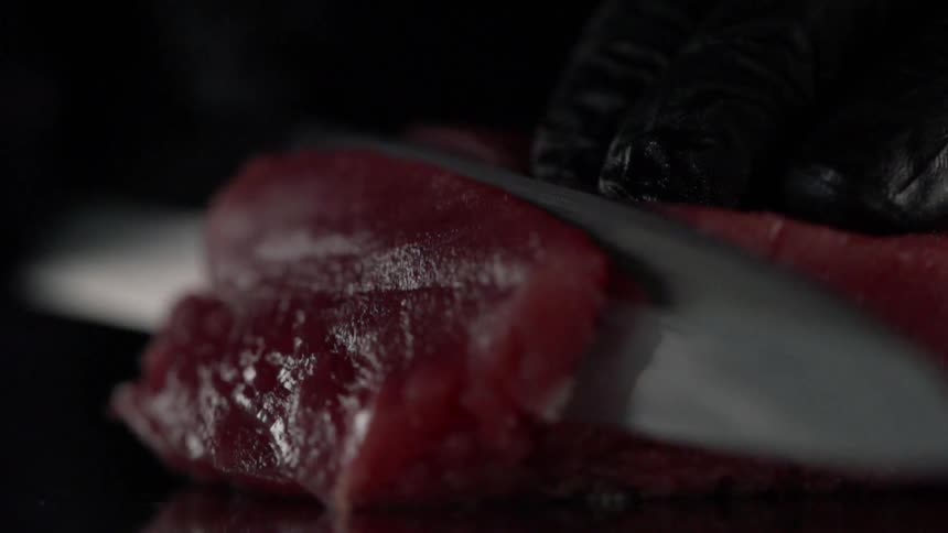 A knife cuts through raw fish