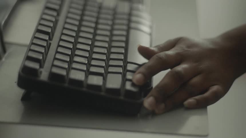 A person taps keys on a keyboard and works equipment
