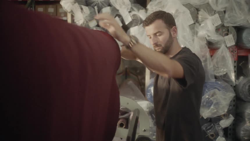 A man unfurls fabric from a spool