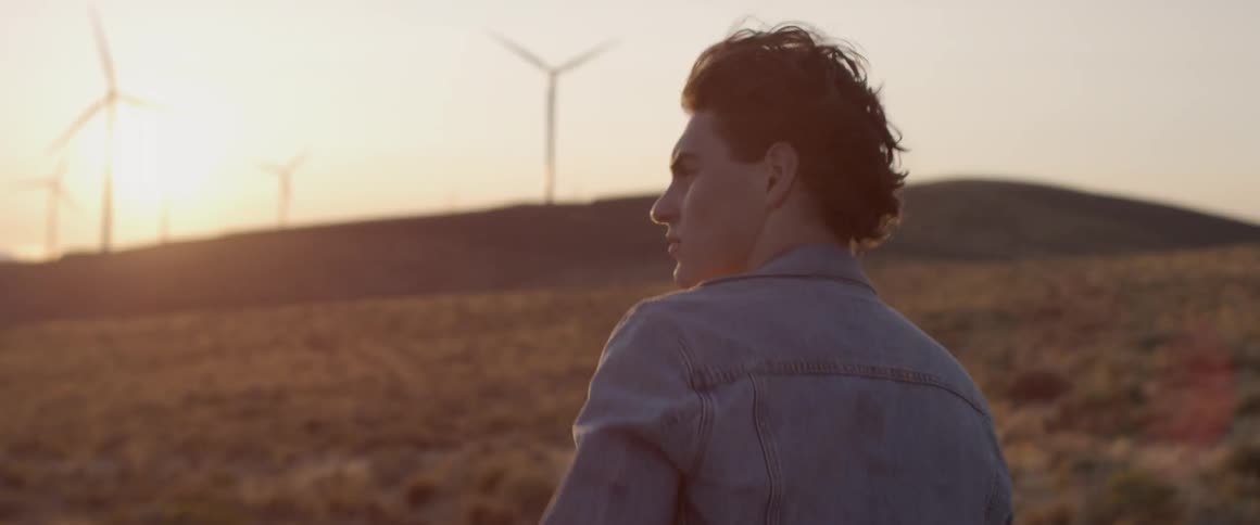 Man walks in a field near the wind turbines