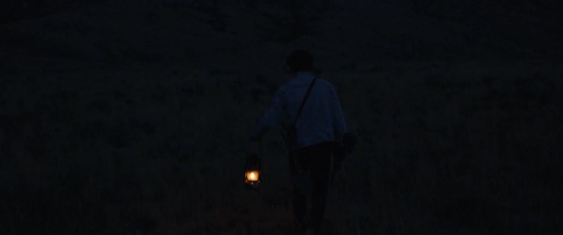 A man walks outside with a lantern