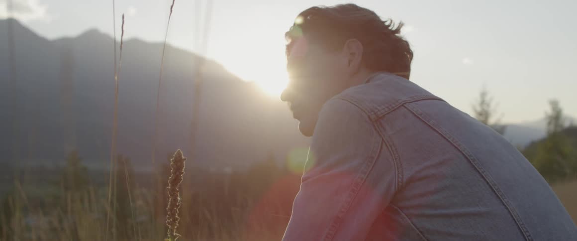 Man sits in a field as he looks around