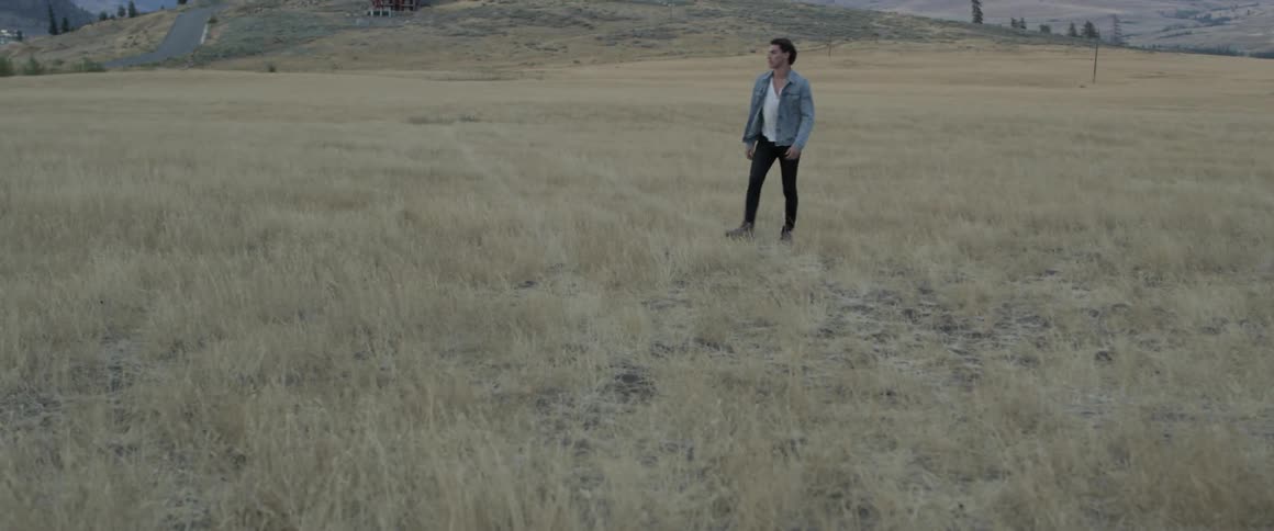 A man is walking through the yellow grass