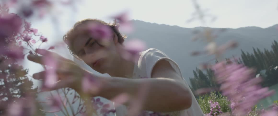A man feels the purple flowers outside