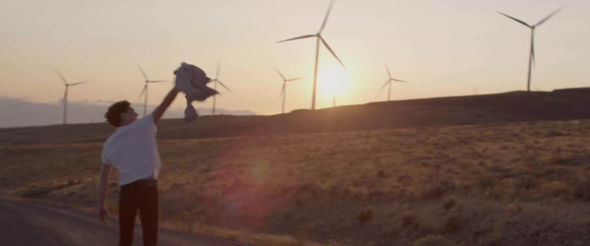 Man carries a jacket on a windy day and raises it above his head