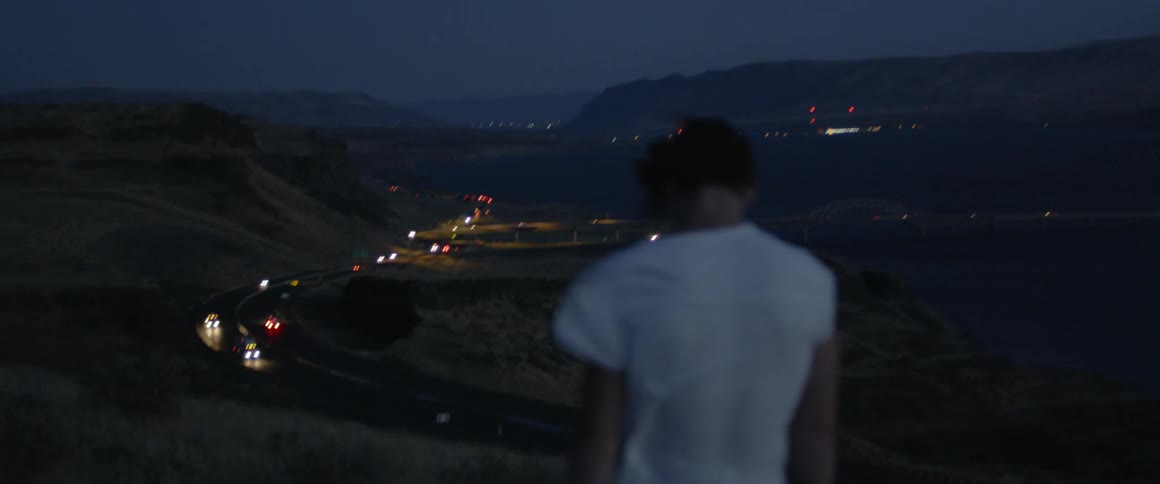 A man walks on the hill above the road at dawn