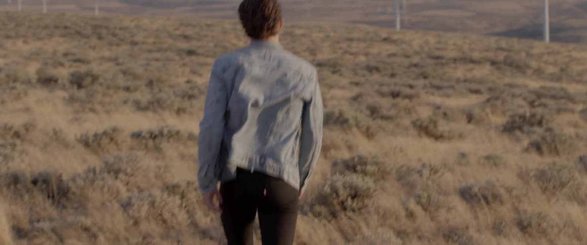 Man walks in windy field of wind turbines