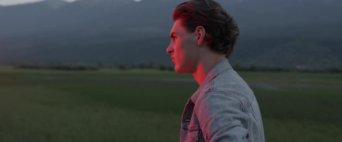 A man stands on the long field looking around