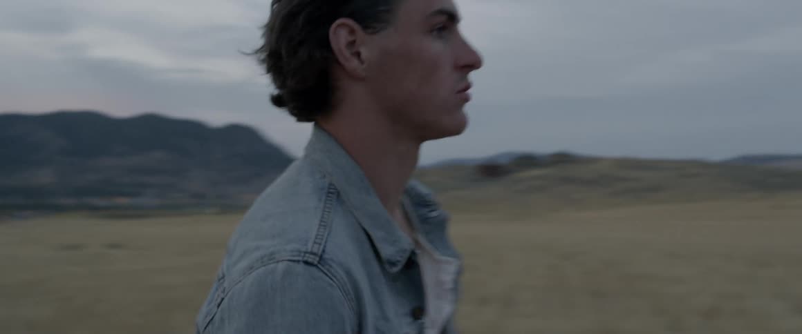 A man walks over the field at sunset