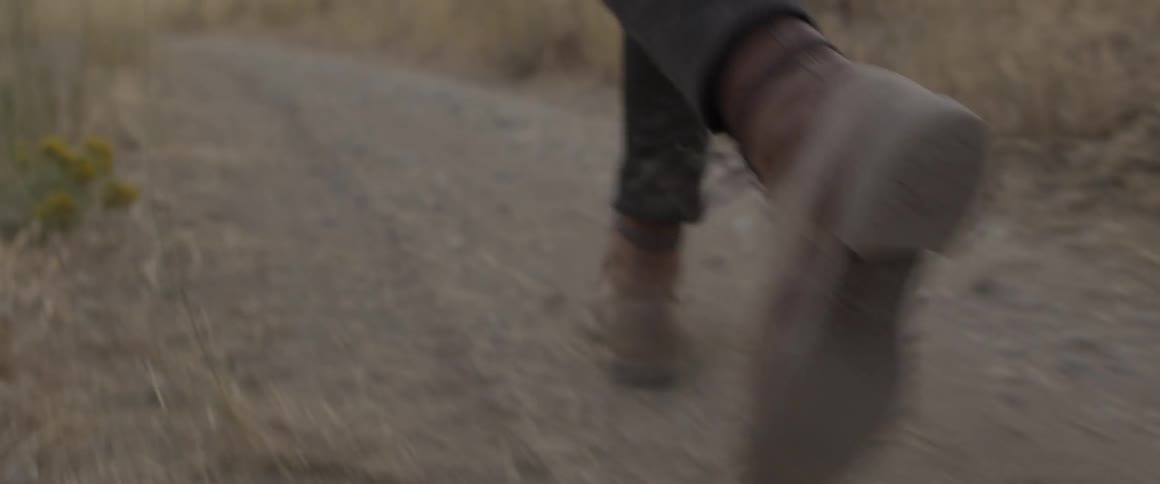 Man wearing boots walks on a dirt path