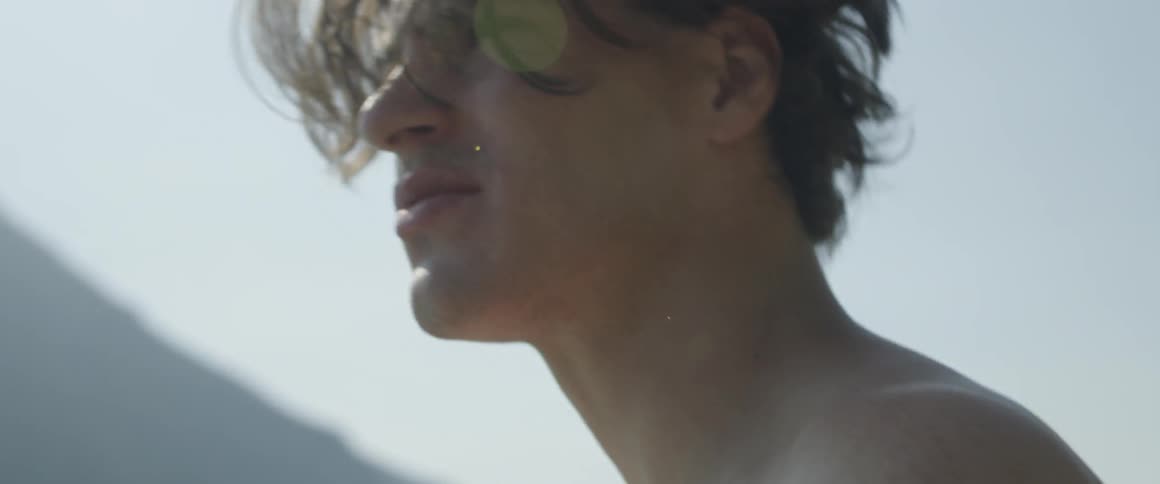 A man pulls his tee shirt off outside
