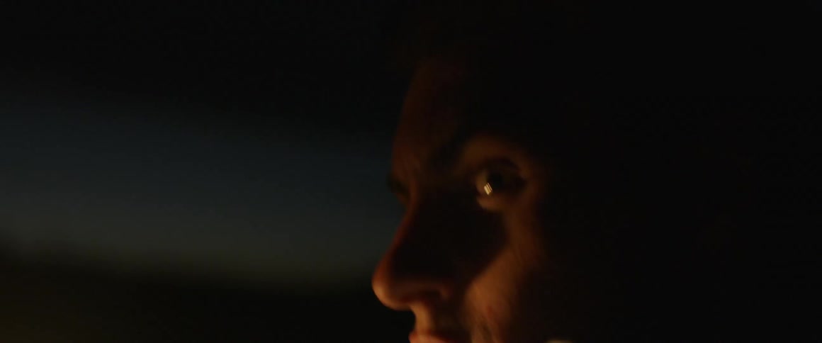 A man walks outside at night with a light to illuminate