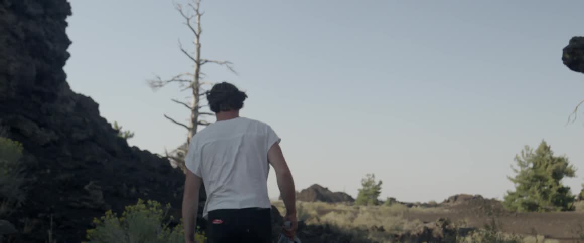 A man in a tank top walks outside