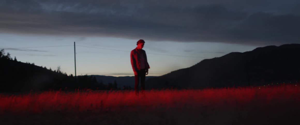 Man stands alone in field at night