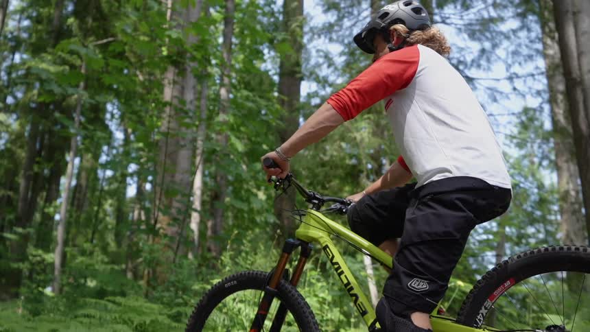 A man wearing a helmet sits on a mountain bike in the woods