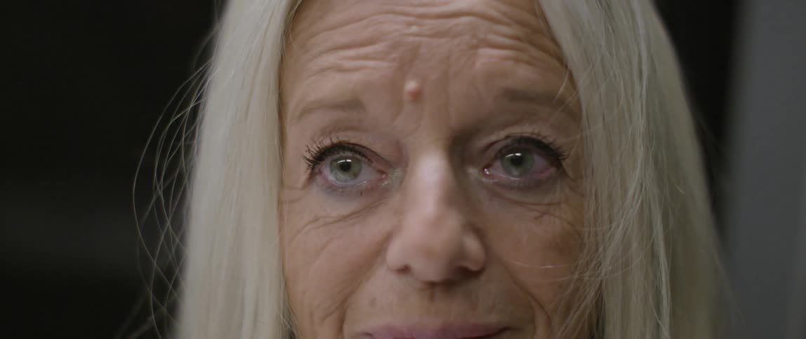 An older woman looks forward while smiling