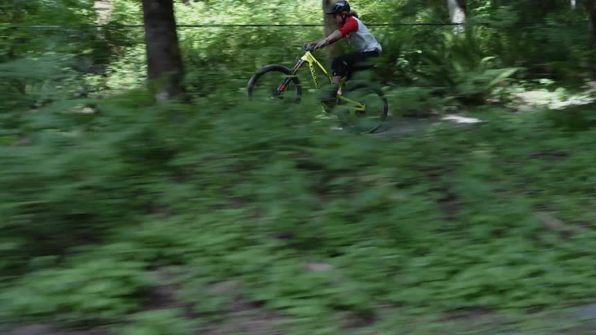 A mountain biker rides on a dirt trail doing tricks