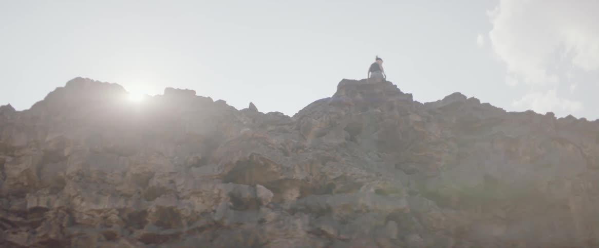 A woman steps towards the rocky cliff