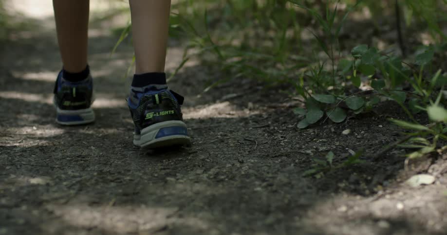 A boy walks on a dirt path