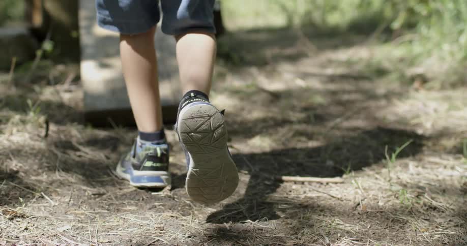Boy is walking outside on dirt path and up wooden board