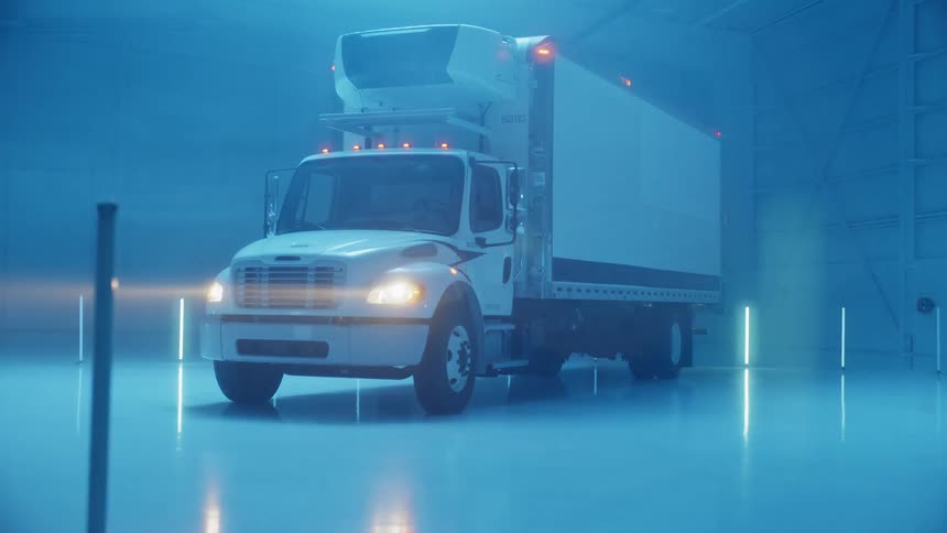 White semi truck parked in a large garage illuminated by blue lights