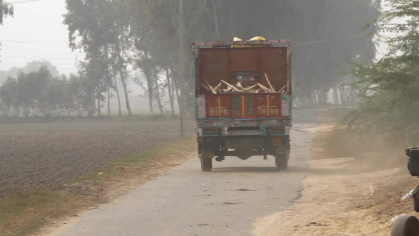 A loaded truck travels on a rural road