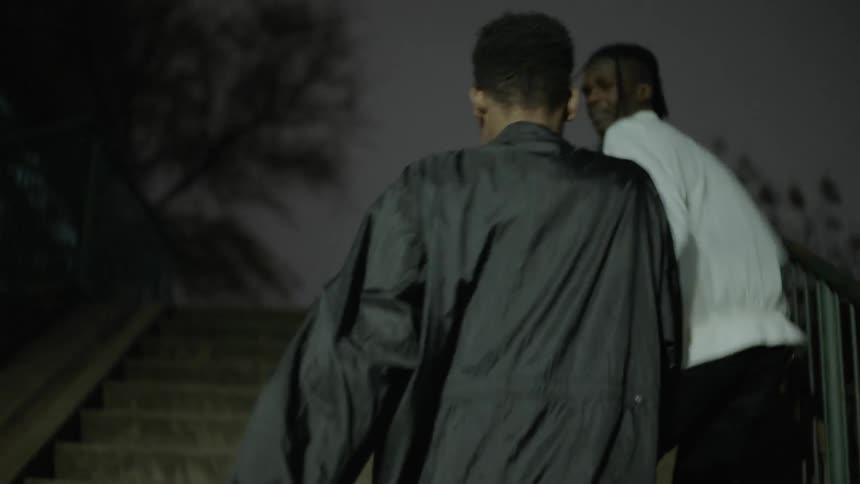 Two people walk up a staircase outside at night