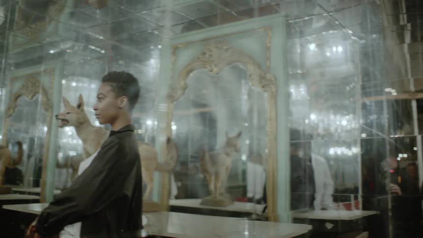 A man approaches a woman in a mirrored room