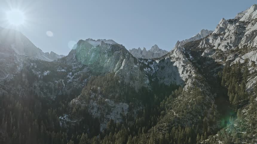 The sun is shining down on a mountain range during the day