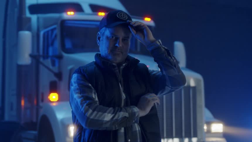 A truck driver stands in front of a big rig truck