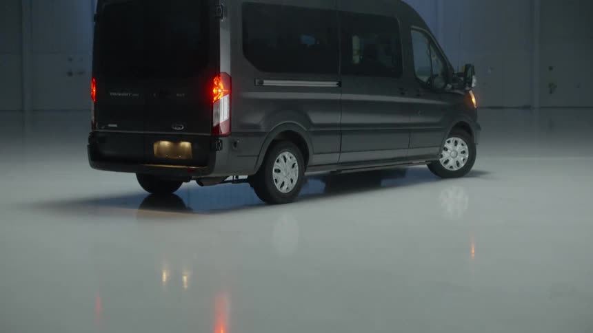 A commercial van is sitting in a warehouse as a light moves across the walls