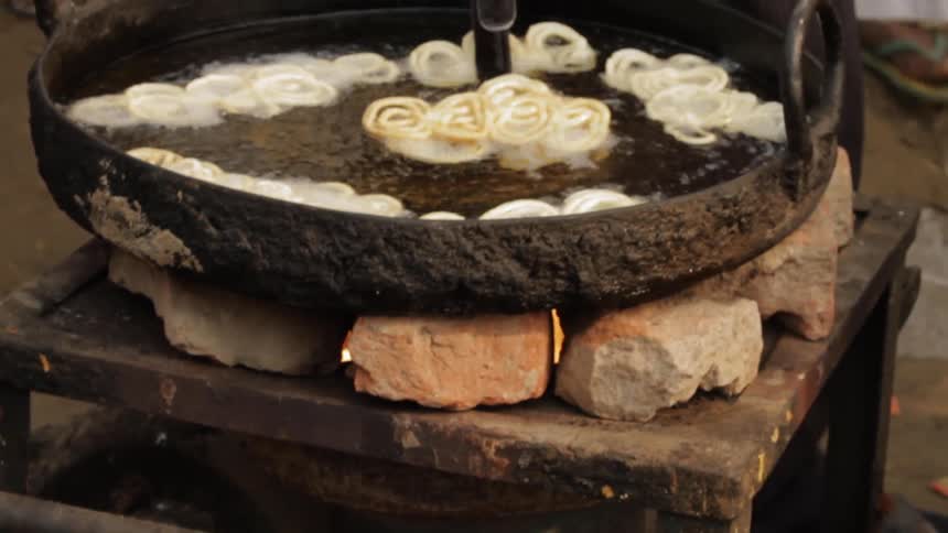 Person sits a pot with fried dough in it