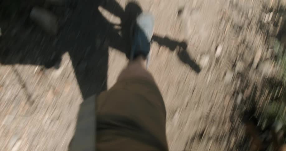 A hiker's shadow on the ground shows ski poles in his hands