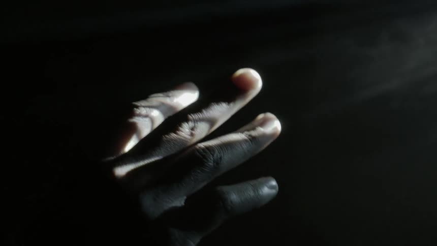 A hand is held up into projected light
