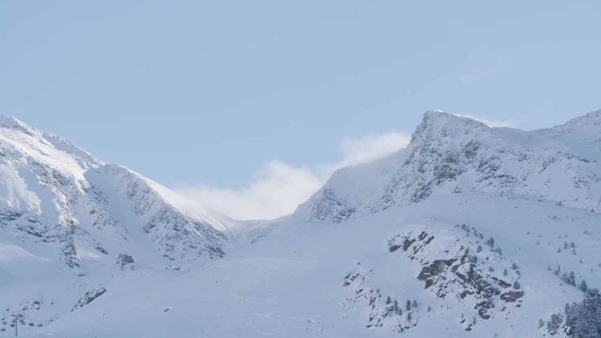 Clouds hang above the snow covered mountain