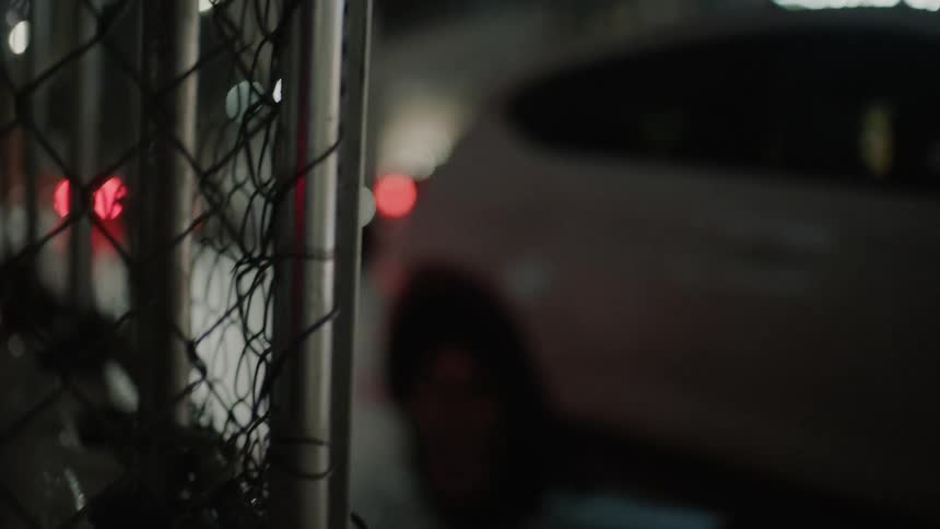 White vehicle drives down a city street at night