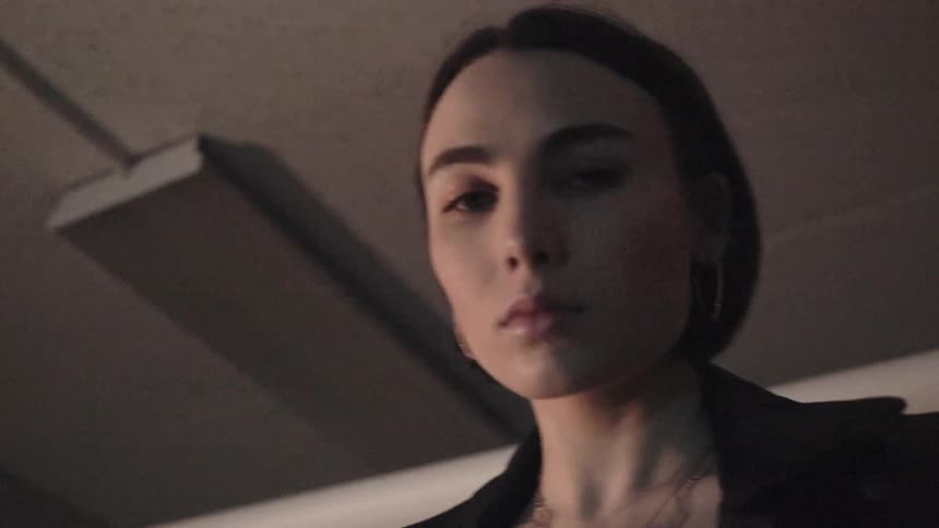 A woman looks down in a dim room