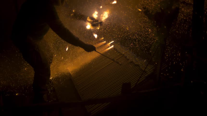 Flames sparking as a person stands over it in the dark