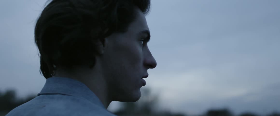 Man is standing outside on cloudy evening and looking around him