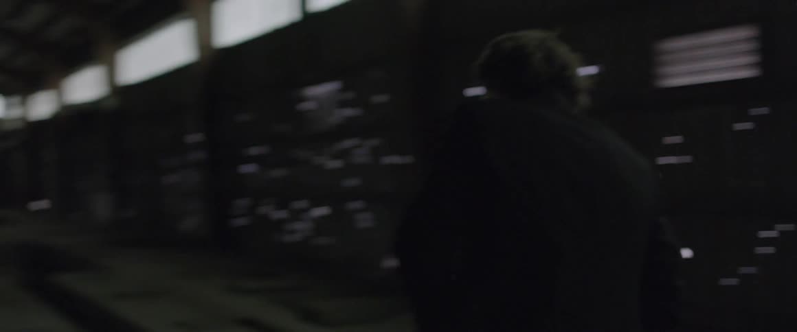 A man walking around inside an empty building at night waving his hand and looking upset