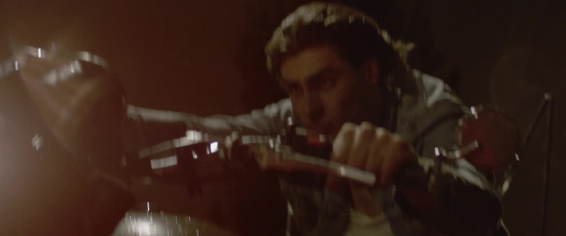 A man is gripping the handle bars of a motorcycle as he rides outside at night