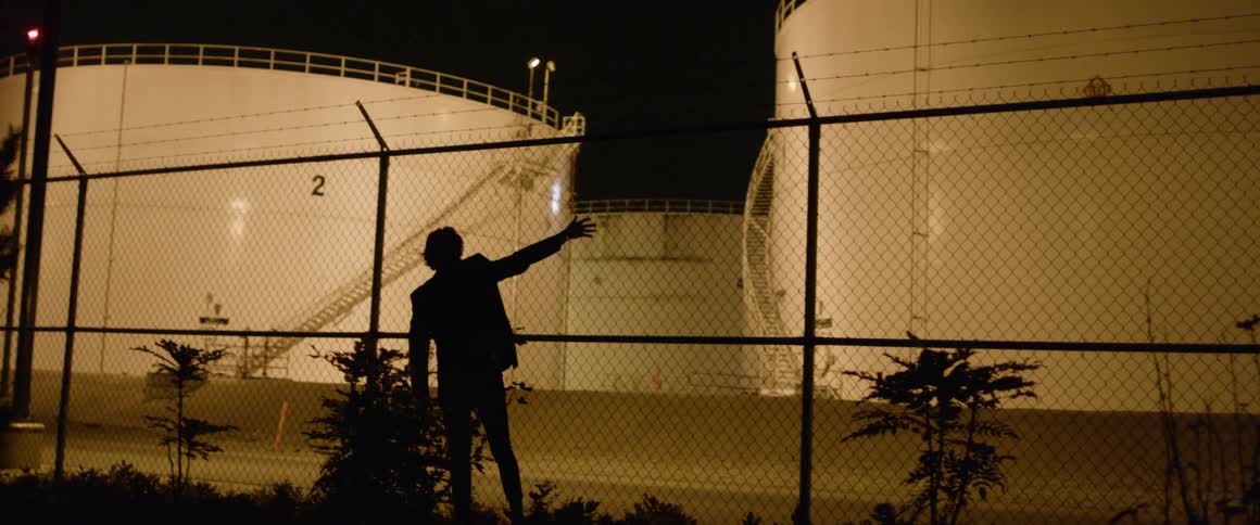 A man grabs onto a tall fence