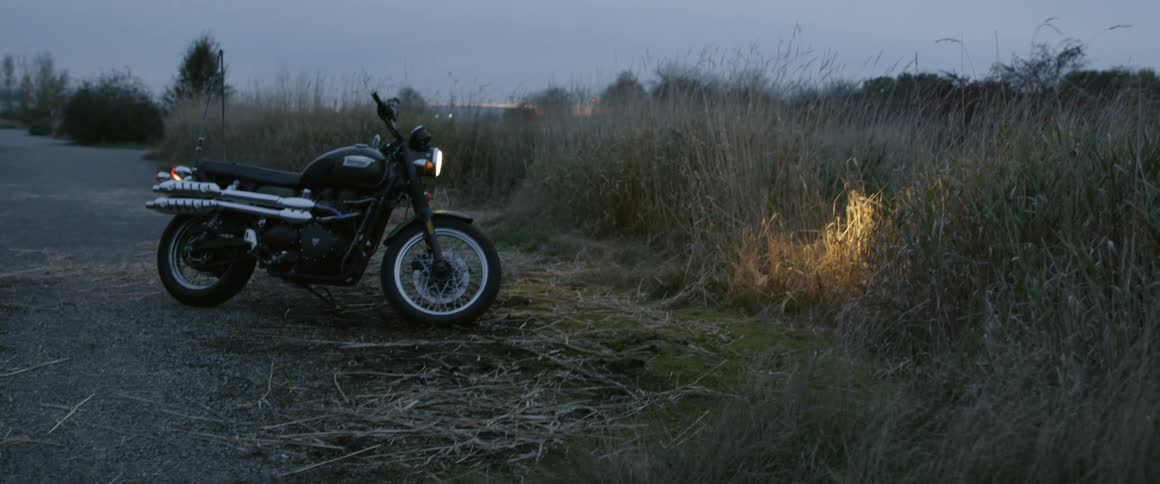 A motorcycle is parked in a rural field at dusk